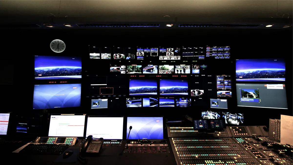 Control room with a wall of monitors above the operators' consoles
