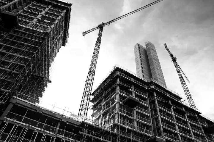 Immeubles en construction sous échafaudages, avec des grues à tour