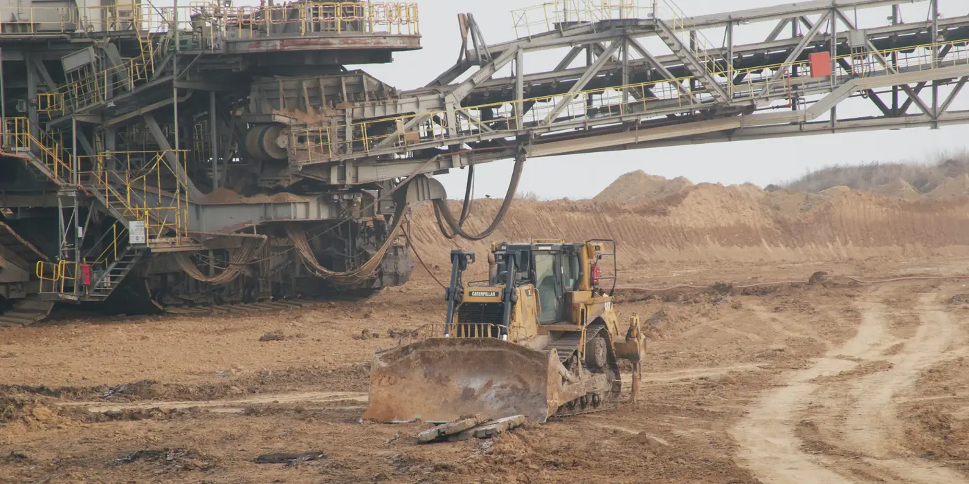 Un bouteur Caterpillar au travail sous la flèche d'une excavatrice à roue-pelle, dans une mine à ciel ouvert
