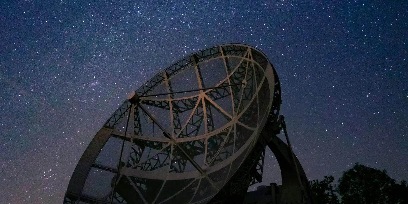 A radio telescope dish under the Milky Way at night